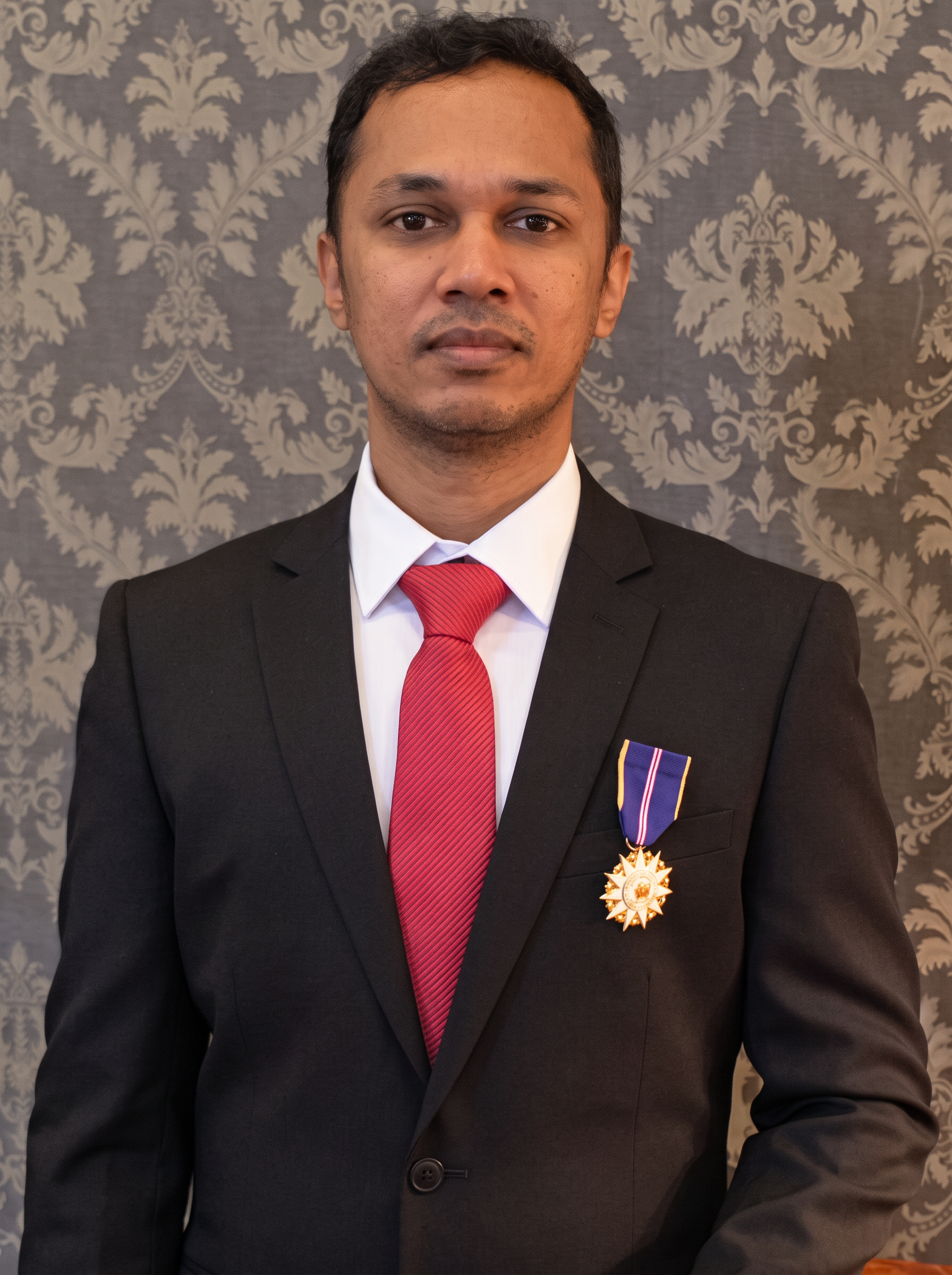 Mr Kumaraveelu in a dark suit wearing the Ahli Mangku Negara medal